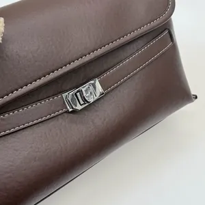 Dettaglio borsa in pelle marrone con chiusura a scatto argentata e cuciture bianche a vista