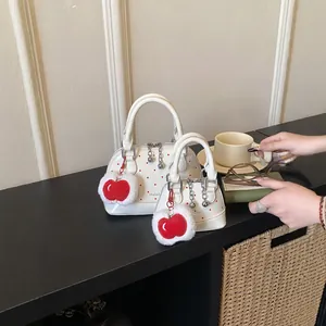Elegant white polka dot handbag with red apple plush charm and silver chain accents
