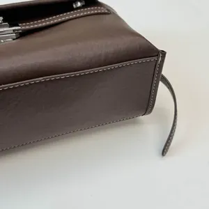 Dettaglio della trama in pelle marrone scuro con cuciture bianche a contrasto e fibbia