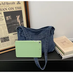 Détail du sac fourre-tout en jean bleu avec broderie SUBELETING et une tablette