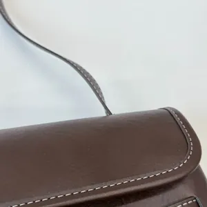 Dettaglio della borsa marrone scuro con cuciture bianche a contrasto e texture in pelle