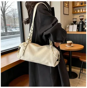 Detail of cream Boston bag featuring pebbled leather texture and metal eyelet straps