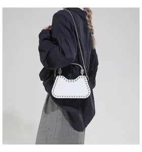 Detailed view of white studded shoulder bag with silver handle and metal chain strap