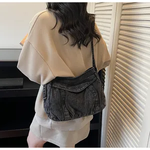 Sac bandoulière tendance en denim délavé gris foncé porté par un mannequin en studio