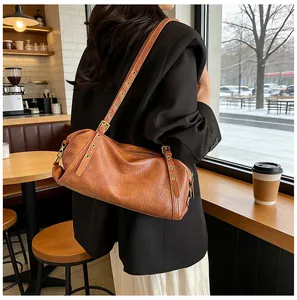 Detail of vintage brown leather Boston bag with metal eyelet adjustable shoulder strap