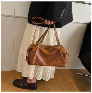 Detailed side view of vintage brown Boston bag with textured leather and metal rivets