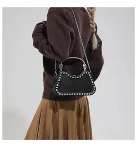Detail of a black leather hobo bag with silver studs and a decorative metal handle