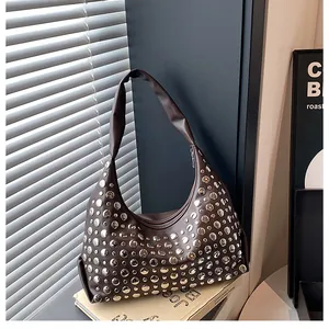 Dettaglio della borsa tote marrone vintage con rivetti argentati e tracolla in pelle