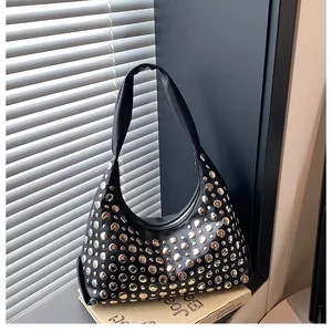 Dettaglio della borsa hobo nera con borchie argentate su uno sfondo urbano di classe