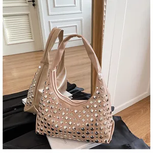 Dettaglio delle borchie argentate su una borsa hobo in pelle beige in uno specchio