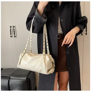 Detail of soft beige leather shoulder bag with metallic eyelet straps and gold hardware