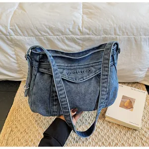 Détail du sac cabas en jean bleu avec broderie SUBELETING et poche avant à rabat