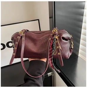 Detailed macro view of dark burgundy pleated leather Boston bag with gold hardware