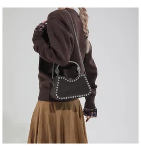 Detail of studded dark leather shoulder bag with metallic handle and chain strap