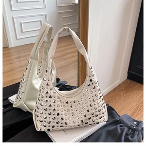 Dettaglio specchio della borsa hobo crema con borchie metalliche e chiusura a zip