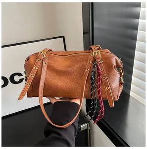 Detail of a brown Boston bag showing leather texture and woven tassel charm accents