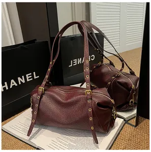 Detail of burgundy leather Boston bag featuring gold eyelets and unique pleated texture