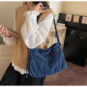 Détail de la broderie sur un sac hobo en jean bleu foncé avec bandoulière réglable