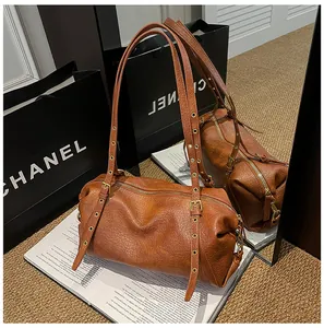 Detailed view of caramel Boston bag featuring textured leather and gold eyelet straps