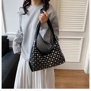 Dettaglio borsa hobo nera con borchie metalliche argentate indossata da modella