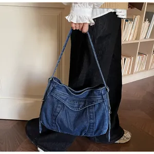 Détail d'un sac cabas en jean bleu avec broderie de lettres et texture plissée