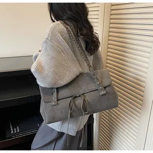 Dettaglio della borsa tote in pelle scamosciata grigia con lacci e tracolla intrecciata