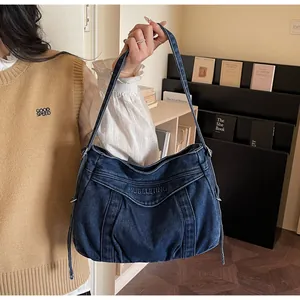 Détail du sac cabas en denim bleu foncé avec lettrage brodé et cordons de serrage
