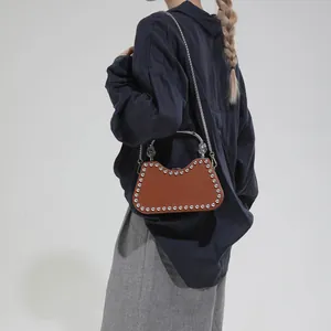 Brown leather shoulder bag with silver rivets and metal handle shown on model