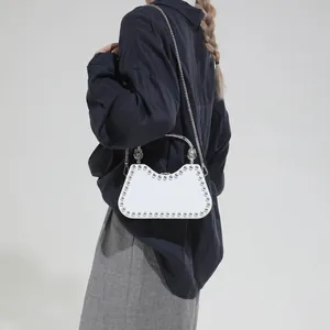 White faux leather crossbody bag with silver rivets and decorative artistic handle