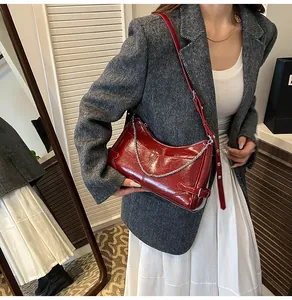 Détail d'un sac en cuir verni bordeaux avec chaîne argentée sur blazer gris
