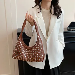 Borsa tote vintage in pelle marrone con borchie su modella in blazer bianco