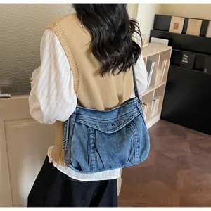 Détail d'un sac bandoulière en denim bleu délavé avec logo Sudeleting embossé élégant