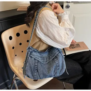 Gros plan détaillé du sac bandoulière en denim délavé bleu avec broderie de lettres élégante