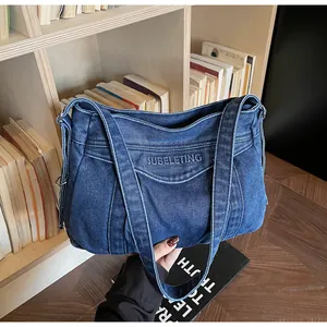 Détail montrant la texture denim et la broderie sur le grand sac fourre-tout