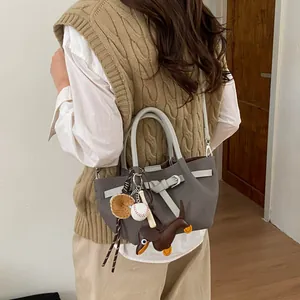 Detailansicht der grauen Retro-Einkaufstasche mit weißen Griffen und Baseball-Anhängern