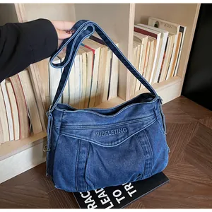 Détail du sac en denim bleu foncé avec broderie de lettres et bandoulière réglable