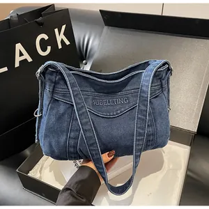 Vue détaillée du sac en denim bleu foncé avec lettres brodées et ferrures métalliques