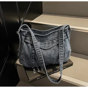 Détail du sac cabas en jean bleu délavé avec broderie SUBELETING et texture plissée