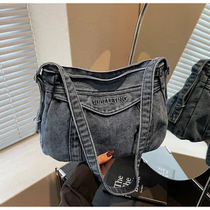 Détail du sac à bandoulière en denim bleu avec broderie et large bandoulière