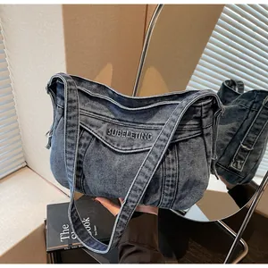 Détail du sac messager en denim bleu avec broderie SUBELETING et large bandoulière