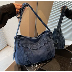 Détail de la bandoulière réglable et de la broderie SUBELETING sur le sac en jean