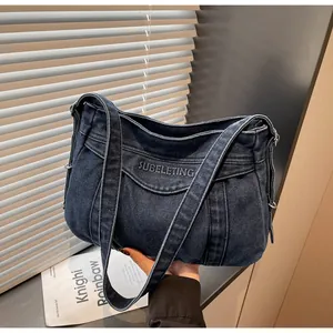 Détail d'un sac cabas en jean bleu foncé avec broderie blanche et boucle métallique