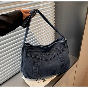 Détail du sac cabas en jean bleu avec lettres brodées et texture en tissu denim délavé