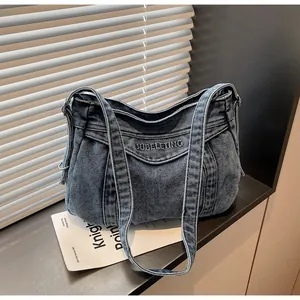 Gros plan détaillé sur la broderie et les coutures du sac à épaule en jean bleu