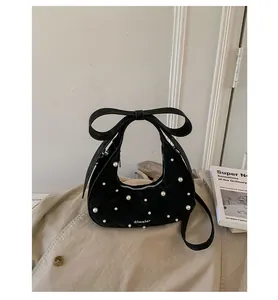 Detail van zwarte gewatteerde hobo tas met parelaccenten en een groot strikhandvat