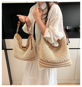 Dettaglio di borse tote in paglia intrecciata a mano con manici in legno e strisce marroni