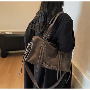 Detail der dunkelbraunen Leder-Beuteltasche mit Fransen und breitem Gurt am Modell