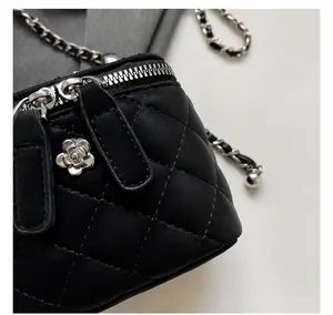 Dettaglio della mini borsa trapuntata nera con catena d'argento e ciondolo camelia
