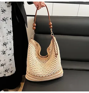 Dettaglio della borsa tote intrecciata con tracolla in pelle marrone e perline di legno