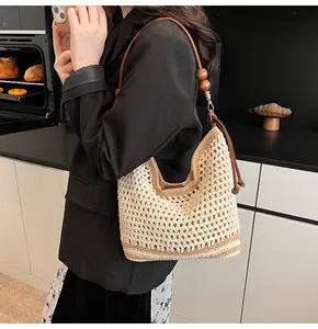 Dettaglio della borsa tote intrecciata con tracolla in pelle marrone e perline di legno